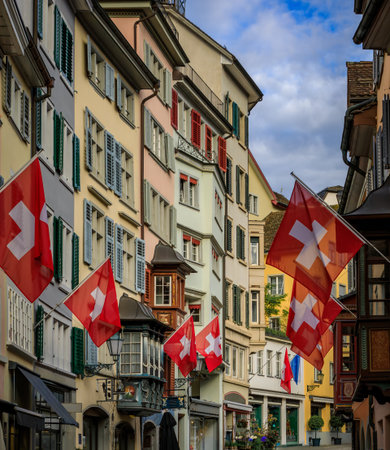 Swiss flags hang from the historic facades of traditional buildings in the Old Town Aldstadt on the famous Augustinergasse street, Zurich, Switzerlandの写真素材