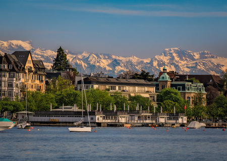 A beautiful serene view of boats on Lake Zurich with the snow covered majestic Swiss Alps visible in the background in Zurich, Switzerlandの写真素材