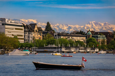 A beautiful serene view of boats on Lake Zurich with the snow covered majestic Swiss Alps visible in the background in Zurich, Switzerlandの写真素材