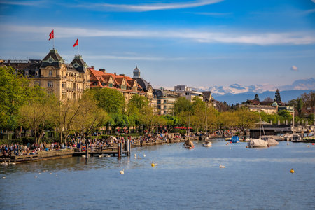 A beautiful serene view of boats on Lake Zurich with the snow covered majestic Swiss Alps visible in the background in Zurich, Switzerlandの写真素材