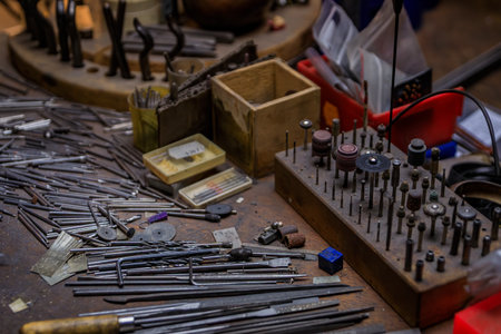 A jeweler s workbench filled with specialized metalworking tools and materials, metal drill bits and...