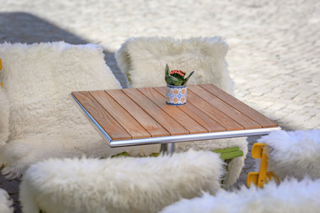 An outdoor cafe table on an Old Town square, surrounded by chairs draped in fluffy white sheepskin...