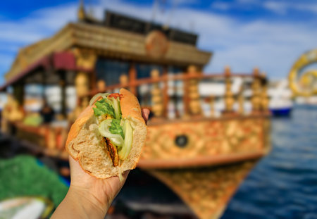 A cook uses tongs to turn fresh fish on a hot griddle, grilling it for a popular fish sandwich, at one of the Balik sandwich boat in Istanbul, Turkeyの写真素材