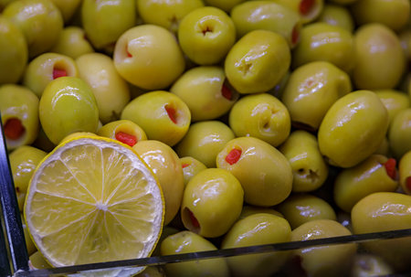A vibrant display of bright green olives stuffed with red peppers on display at the bustling Egyptian Bazaar, Istanbul, Turkey, trade and food cultureの写真素材