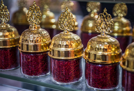 A vibrant display of bright red saffron in an ornate jar with a gold lid at the bustling Egyptian Bazaar, Istanbul, Turkey, trade and food cultureの写真素材