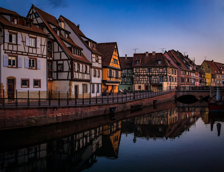 Ornate half timbered houses with blooming flowers along the canals, Little Venice district in Colmar, picturesque village in Alsace France at sunsetの写真素材