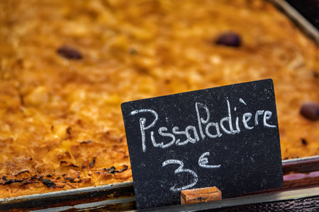 Pissaladiere, a savory provencal tart with onions, olives and herbs on display at a restaurant in Old Town or Vieille Ville of Nice, South of Franceの写真素材