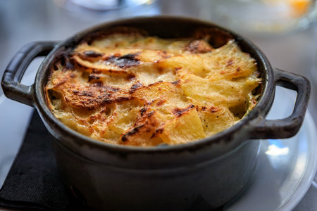 Oven roasted golden brown potato gratin served in a small cast iron pot at a French restaurant in...