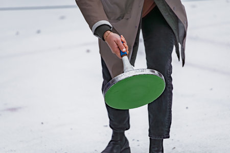 Traditional Swiss winter game, Eisstock sport or Bavarian curling, player prepares to throw a stock on an ice rinkの写真素材
