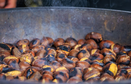 Traditional roasted chestnuts cook in a hot pan at a Christmas market stand, a holiday experience in Zurich, Switzerlandの写真素材