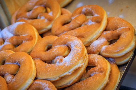 Freshly made sweet pretzels, bretzels or beignets sprinkled with powedered sugar at a Christmas Market stand in Strasbourg, Franceの写真素材
