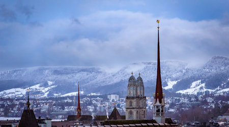 Aerial winter cityscape with iconic Grossmunster twin church towers, and snow covered Uetliberg mountain after a snowfall in Zurich, Switzerlandの写真素材
