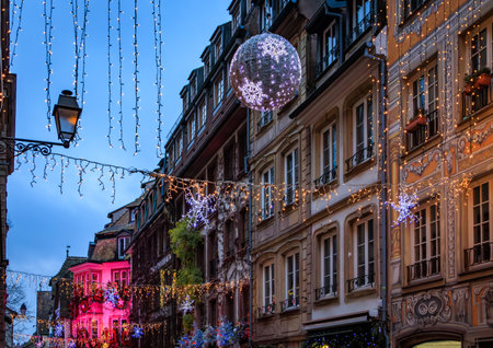 Strings of festive lights illuminate a street with half timbered houses in the Grande Ile district of Strasbourg, France, during the Christmas Marketの写真素材