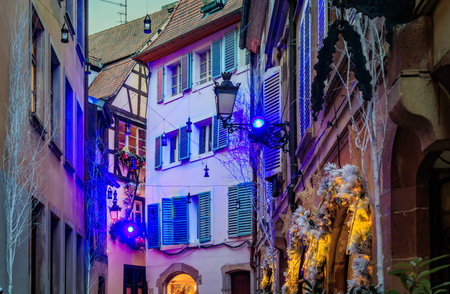 Strings of festive lights illuminate a street with half timbered houses in the Grande Ile district of Strasbourg, France, during the Christmas Marketの写真素材