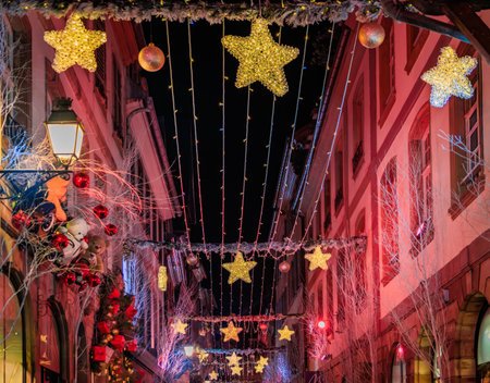 Strings of festive lights illuminate a street with half timbered houses in the Grande Ile district of Strasbourg, France, during the Christmas Marketの写真素材