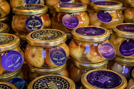 Colmar, France - December 14, 2024: Jars of Baba au Rhum or Rum Baba cakes soaked in pear Poire and damson plum Quetsche liqueurs, Christmas marketのeditorial素材