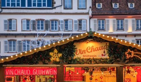 The warm glow of a cozy mulled wine stall with festive lights under the falling snow, a magical scene at the Strasbourg Christmas Market in Franceの写真素材