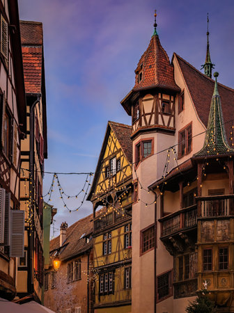 Festive decorations and ornaments on historic half timbered houses glow at sunset during the Christmas Market in the Old Town, Colmar, Alsace, Franceの写真素材
