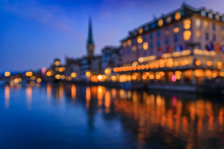 An impressionistic blurred long exposure of a city skyline with glowing lights reflected in the Limmat River, the waterfront in Zurich, Switzerlandの写真素材
