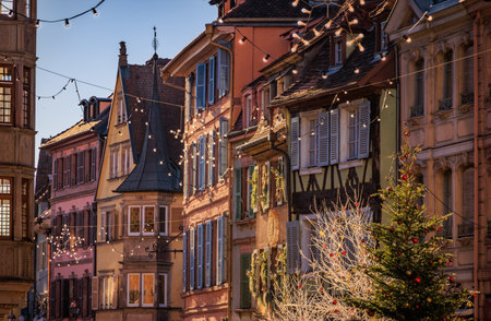 Festive decorations and ornaments on historic half timbered houses glow at sunset during the Christmas Market in the Old Town, Colmar, Alsace, Franceの写真素材
