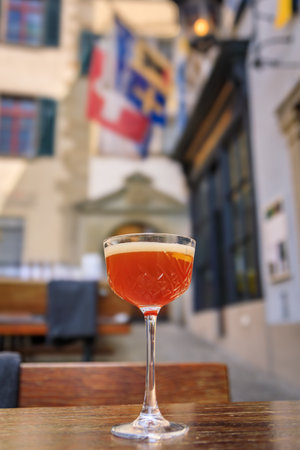 A refreshing cocktail topped with foam on a table at an outdoor cafe with charming Swiss buildings in the Old Town or Altstadt, Zurich, Switzerlandの写真素材