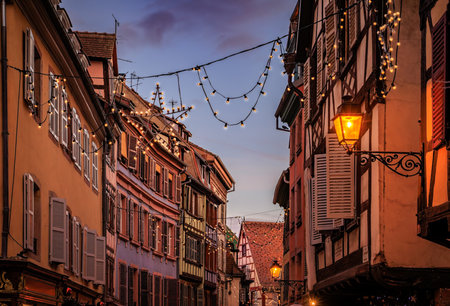 Festive decorations and ornaments on historic half timbered houses glow at sunset during the Christmas Market in the Old Town, Colmar, Alsace, Franceの写真素材