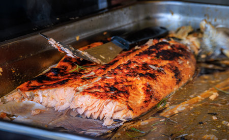 Salmon fillet roasted over an open fire, resting in a pan, served at a restaurant stall at the...