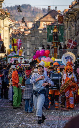 Bern, Switzerland - March 1, 2025: Guggenmusik marching brass band in colorful costumes and face...