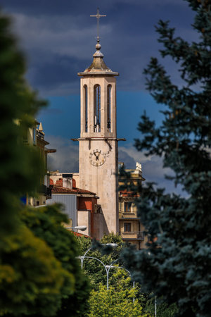 Modern clock tower of the Church of San Lorenzo with an open belfry against dark dramatic clouds and...