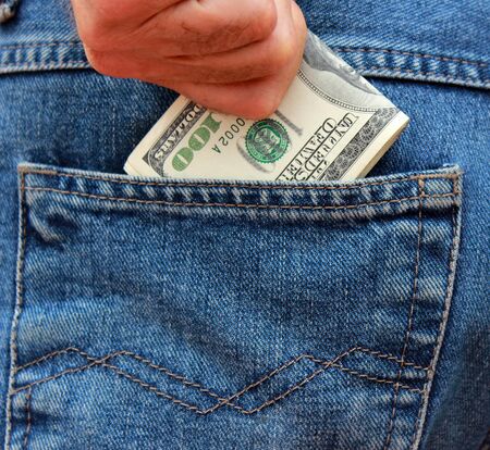 Hand gets dollars from a pocket of jeans