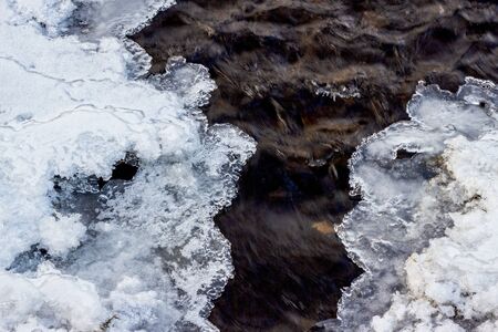 Ice on the river in winter. Picturesque hoarfrost, crystals on river ice over dark flowing water...