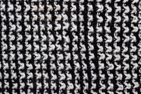 Knitted woolen white and black background. Texture of black and white wool close-up. Knitted fabric,...