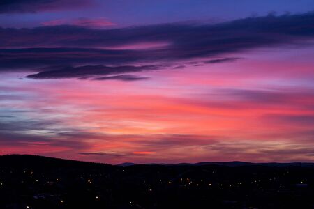 Red-blue-yellow fiery, burning like a flame the evening sky. Beautiful red-blue sunset over city plans with clouds. Dark silhouette of a winter city with beautiful dawn. Artistically blurry.の写真素材