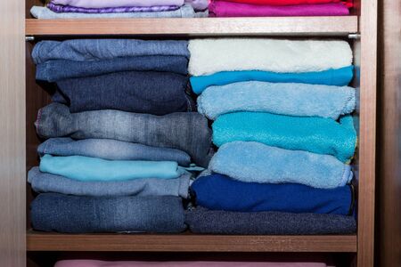 Shelving with warm boy clothes. A wooden cupboard with a stack of blue dark things. Shelf cabinet...