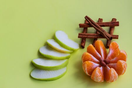 Creative fruit collage of apples, mandarin and cinnamon on a yellow background. Copy space, flat...