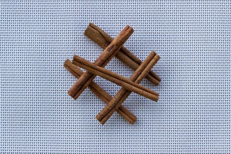 Cinnamon sticks on a white checkered background. Selective focus. Cinnamon sticks isolated on a kitchen napkin. Close-up, copy space.の写真素材