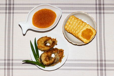 Red caviar in a white dish, a glass of wine with vodka, salted cooRed caviar in a white dish, slices...