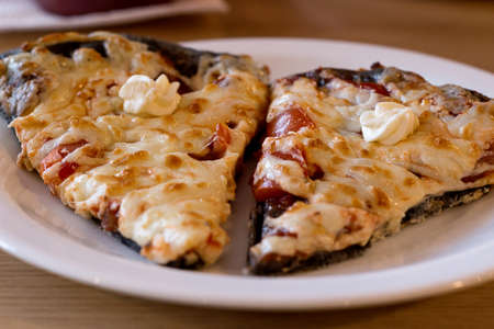 Two pieces of margarita pizza on dark dough. Pieces of freshly baked, hot pizza close-up on a white...
