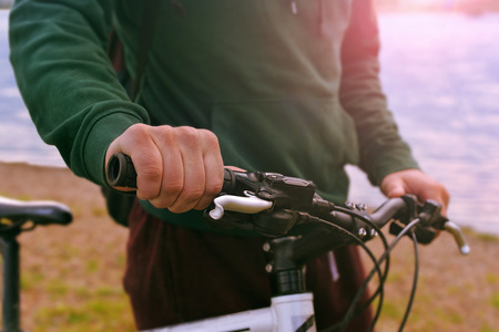 Male hands on a bicycle handle close up at sunset. A man with a bicycleの写真素材