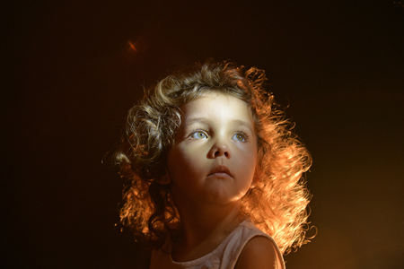 Portrait of a girl on a black background. The face of the child. Studio portrait.の写真素材