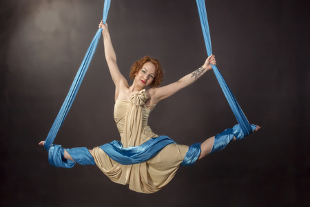 Young woman training flexibility on aerial silkの写真素材