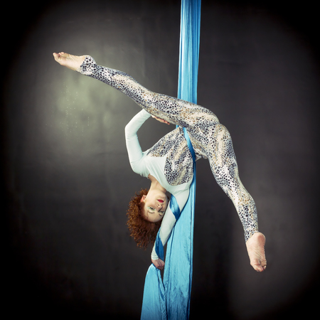 Young woman training handstand on aerial silkの写真素材