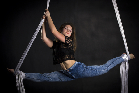 Aerialist woman doing some flexibility and strength tricks on silksの写真素材