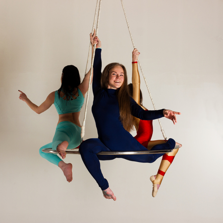 Young woman`s trio doing som acrobatic tricks on aerial lusterの写真素材