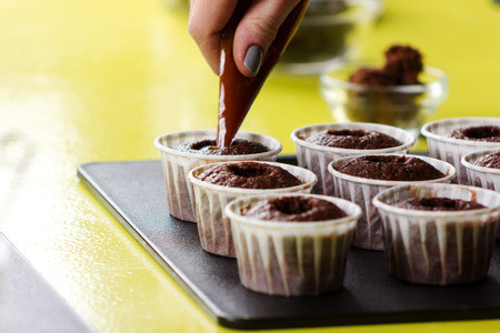 Process of decorating cupcakes on the table in kitchenの写真素材