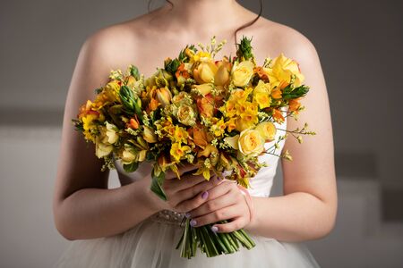 Beautiful bride in white dress with bouquet in photostudio at gray backgroundの写真素材