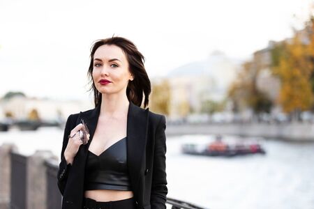 Beautiful woman in black pantsuit walks on promenade in Saint-Petersburgの写真素材