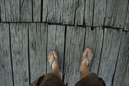 Feet of Feet of man on old wooden bridge.