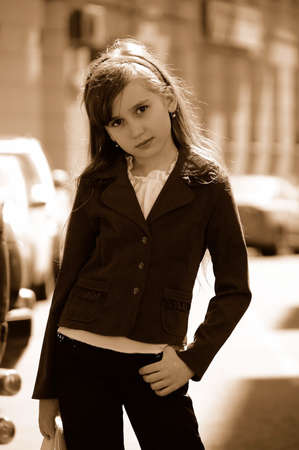 A girl of 9 years old is standing in the street and is looking seriously into camera.の写真素材