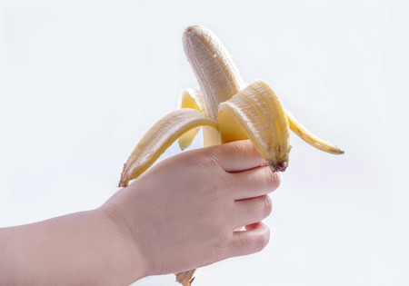 Hand holding a peeled banana isolated on white background.の写真素材